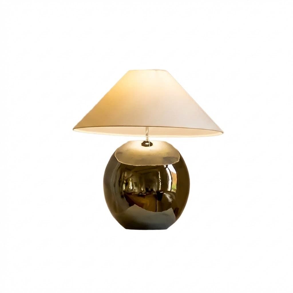 A table lamp with a spherical base and a conical lampshade. The base appears to be made of a reflective, possibly ceramic or metallic material, with a glossy finish. The lampshade is a neutral color, likely fabric, and is illuminated from within, casting a warm light. The design is modern and elegant. — 3D model