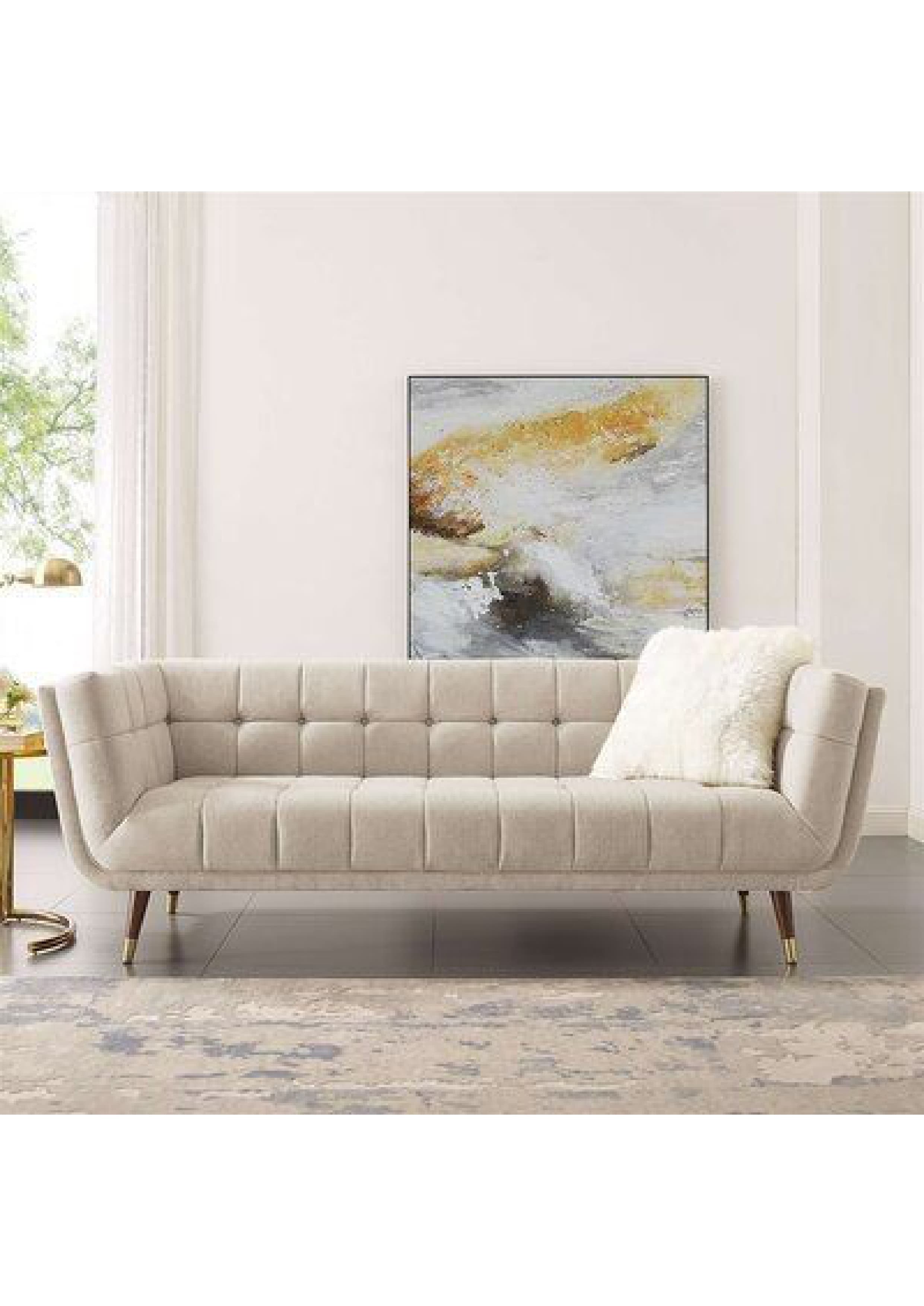 A contemporary three-seater sofa featuring deep button tufting across the back and seat, upholstered in a light beige fabric, and supported by tapered wooden legs with brass ferrules. — 3D model