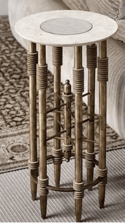 A tall, elegant pedestal table featuring a round white marble top with a subtle inset, supported by a cluster of polished brass columns. The brass columns are adorned with textured rope-wrapped accents at the top and bottom, and a decorative, cross-braced brass element at the mid-section adds structural and visual interest. — 3D model