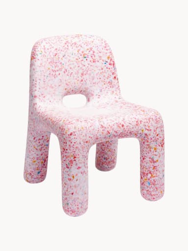 A small, child-sized chair made entirely from a single molded piece of recycled plastic, featuring a distinctive speckled or confetti-like pattern. The chair is predominantly white with multi-colored fragments (red, orange, yellow, blue, green) embedded throughout the material. It has a simple, monolithic design with rounded edges and a backrest, and an oval cutout in the seat. — 3D model