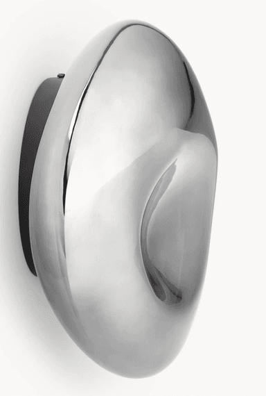 A modern wall-mounted light fixture featuring a fluid, organic, and irregularly shaped front in a highly polished chrome or metallic finish. It is mounted on a flat, dark backplate, contrasting with the reflective, undulating surface of the main light element. The design is sculptural and abstract, intended to provide ambient light while serving as a decorative art piece. — 3D model