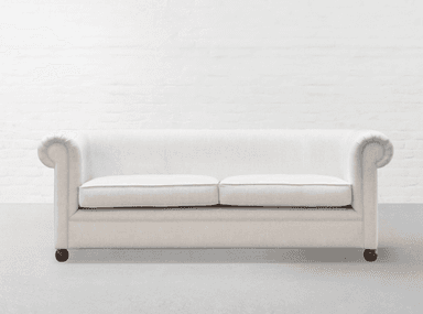 A cream-colored, two-seater loveseat featuring a traditional design with gracefully rolled arms and an upholstered back. It has two separate loose seat cushions, each with subtle piping along the edges, and rests on short, dark-colored turned legs. — 3D model