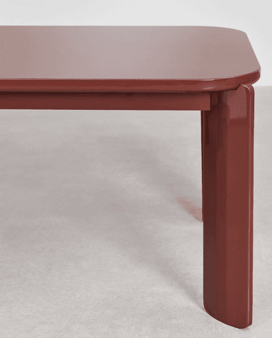 A close-up view of a table's corner and one leg. The table has a rectangular top with rounded corners and a thick, slightly beveled edge. The leg is solid and rectangular in cross-section, with a subtle taper towards the bottom and a rounded end. The design appears modern and minimalist. — 3D model