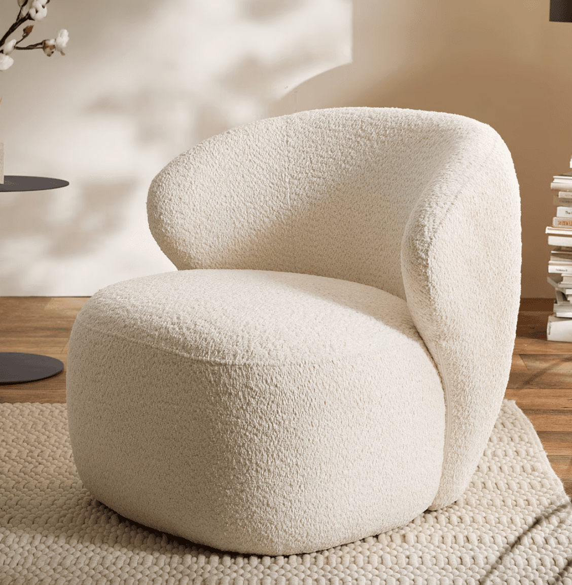 A contemporary lounge chair upholstered in a textured, cream-colored bouclé fabric. The chair features a distinctive, organic silhouette with a rounded back that seamlessly transitions into the armrests and seat, creating a unified and inviting form. Its low profile and plush cushioning suggest comfort and relaxation, making it a statement piece for modern interiors. — 3D model