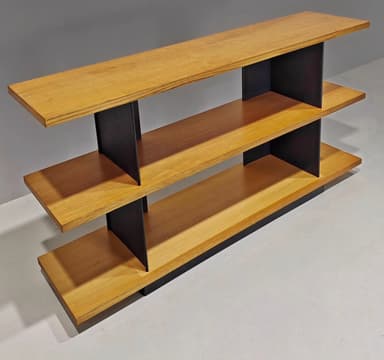 A modern, multi-tiered console table featuring three horizontal wooden shelves supported by contrasting vertical black elements. The top shelf extends over the middle, which in turn extends over the base, creating a cantilevered and layered appearance. The black supports are angled, providing a geometric and stable structure. — 3D model