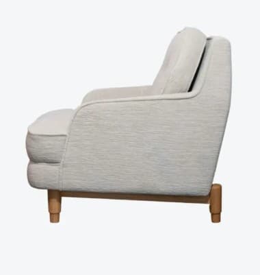 A upholstered armchair with a tufted back cushion. The armchair features a rounded silhouette with padded arms and a fixed seat cushion. It is supported by four tapered wooden legs. — 3D model