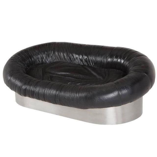 A low-profile sofa with an oval-shaped silhouette. The upholstery features a tufted or gathered effect around the perimeter, creating a distinctive textured edge. The base appears to be constructed from a smooth, polished metal material, providing a contrasting element to the soft upholstery. — 3D model