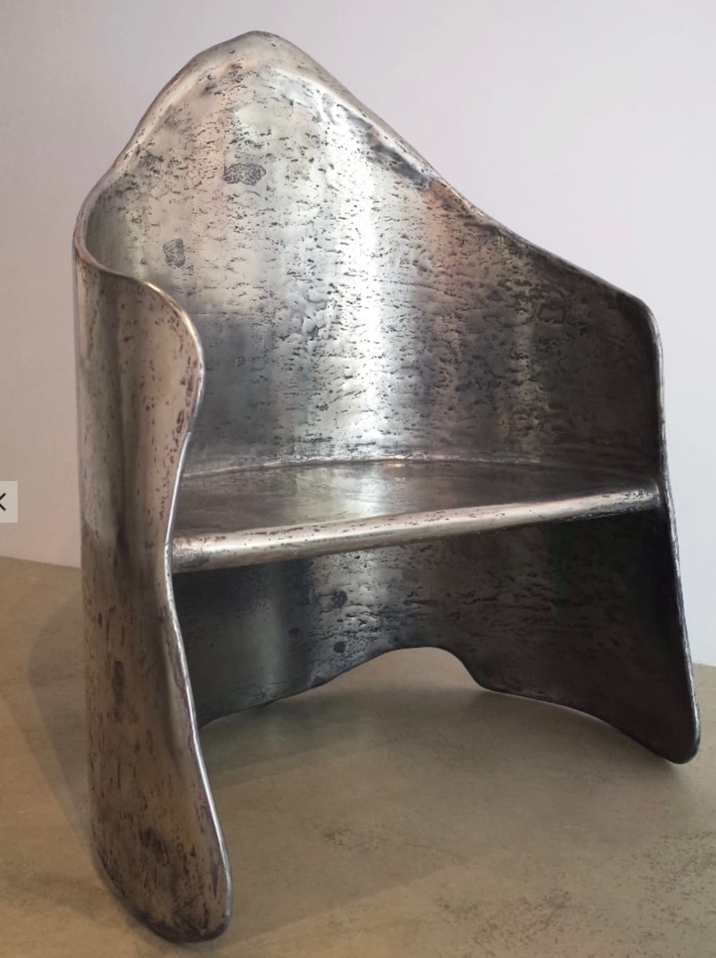 A contemporary accent chair with a distinctive, sculptural design. The chair features a high, curved back that wraps around the sides, forming armrests. It has a molded seat and a supportive backrest. The overall form is organic and flowing, with a prominent, pointed apex at the top of the back. — 3D model