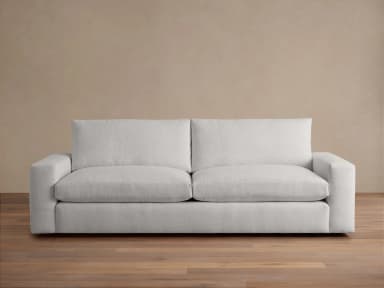 A modern, upholstered sofa viewed from the back. It features clean lines, square arms, and a relatively low profile. The upholstery appears to be a textured fabric in a light color. The sofa has two distinct back cushions and an extended base. — 3D model