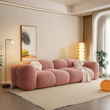 A contemporary pink modular sofa featuring a distinctive segmented, bubble-like design for both its seating and backrest, upholstered in a plush fabric. It is adorned with two round, cream-colored decorative pillows and a light-colored knitted throw blanket. — 3D model