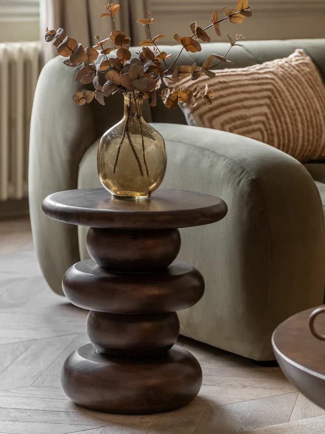 A dark brown side table with a circular top and a stacked, segmented pedestal base. The base features three distinct bulbous sections separated by narrower cylindrical segments, giving it a sculptural, almost spindle-like appearance. The overall form is rounded and organic. — 3D model
