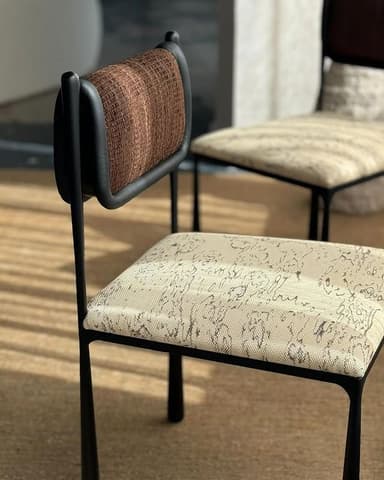 A modern side chair with a metal frame, upholstered seat, and upholstered backrest. The frame is black and features tapered legs. The seat is upholstered in a light-colored fabric with a black patterned print. The backrest is upholstered in a textured brown fabric and is integrated into the frame. — 3D model