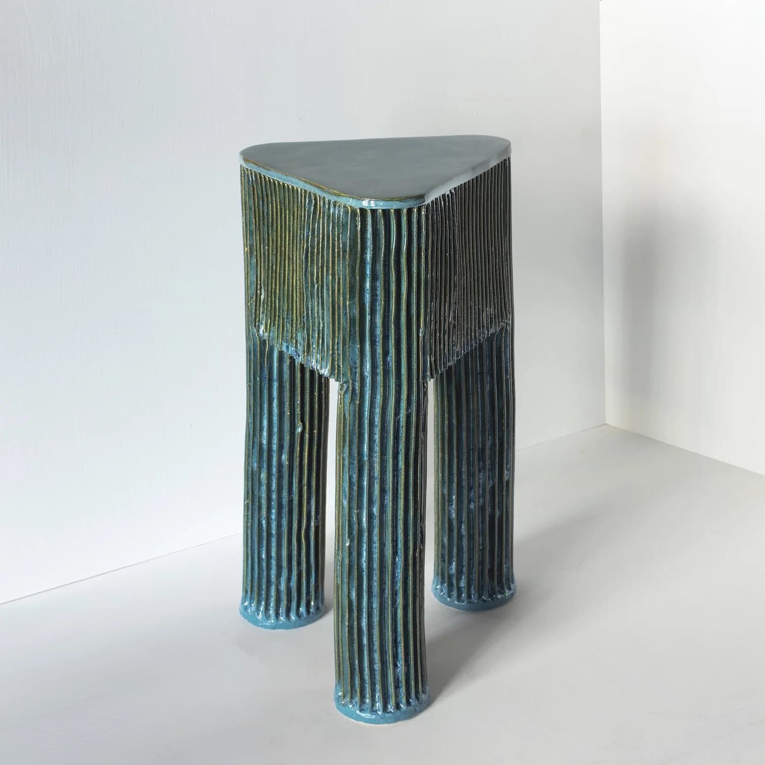 A striking accent table with a unique triangular top and three supporting columnar legs. The entire structure is characterized by a finely fluted, vertical texture and finished with a rich, verdigris blue-green patina that reveals hints of a golden-bronze undertone. The table is compact and designed as a standalone decorative piece. — 3D model