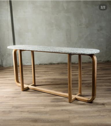 A modern console table featuring an elongated oval tabletop made of speckled grey stone, supported by a minimalist wooden base. The base consists of two U-shaped wooden frames, connected by a horizontal stretcher bar near the bottom, creating a light and airy aesthetic. — 3D model