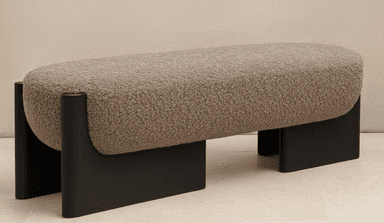 An elongated, pill-shaped bench featuring a textured boucle fabric upholstery in a neutral beige/taupe color. The bench is supported by two substantial, C-shaped or U-shaped legs made of dark-stained wood, creating a modern and minimalist aesthetic. — 3D model