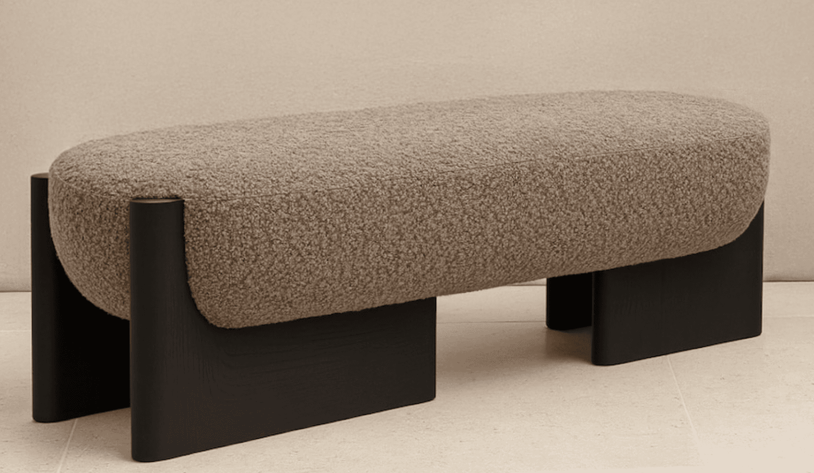 An elongated, pill-shaped bench featuring a textured boucle fabric upholstery in a neutral beige/taupe color. The bench is supported by two substantial, C-shaped or U-shaped legs made of dark-stained wood, creating a modern and minimalist aesthetic. — 3D model