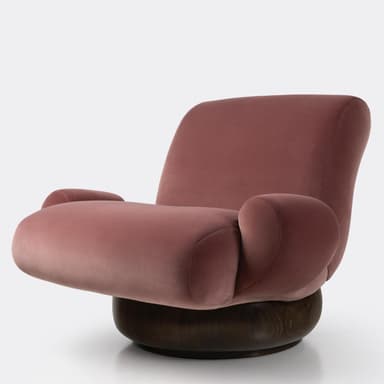 A contemporary lounge chair featuring a distinctive sculptural form. The upper body is upholstered in a plush, dusky pink velvet fabric, creating soft, organic curves that form the seat, backrest, and integrated armrests. This upholstered section rests upon a substantial, dark stained solid wood base that is round and bulbous, providing stability and a swivel function. The chair has a low profile and an inviting, enveloping design. — 3D model