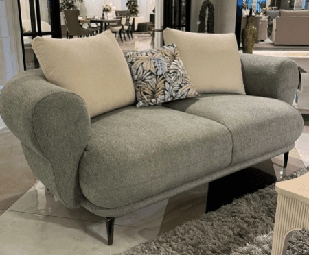 A contemporary two-seater loveseat with a rounded silhouette, upholstered in a textured sage green fabric, featuring tapered black legs and accompanied by three throw pillows. — 3D model