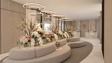 A large, modular, curved banquette sofa upholstered in a light beige textured fabric, featuring a multi-tiered design. The lower tier forms the main seating, while a higher, inner tier integrates a curved marble-topped surface used as a planter or display area, adorned with floral arrangements. The entire unit follows a sweeping, organic curve, designed for public or commercial spaces. — 3D model