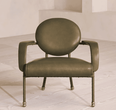 A contemporary armchair with a rounded backrest and armrests, upholstered in a muted olive-green material. The frame appears to be made of metal with a dark finish, and the legs are slender with decorative brass caps. — 3D model