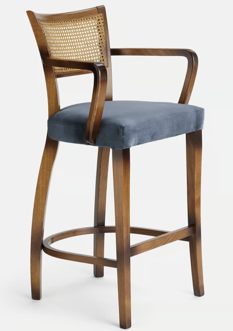 A bar stool with a wooden frame, featuring a cane-woven backrest and a padded seat. The stool has a high profile suitable for a bar or counter, with integrated armrests and a footrest ring connecting the legs. — 3D model
