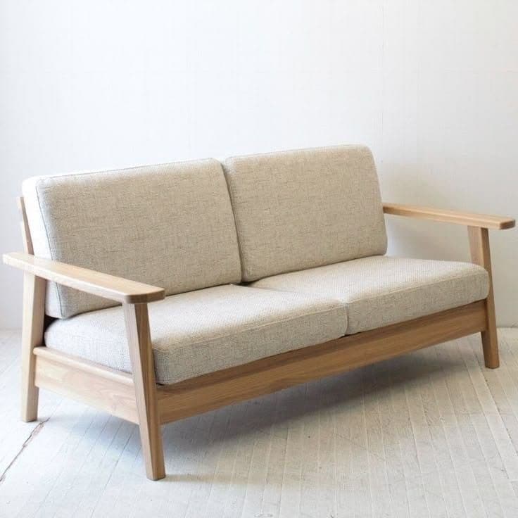 A modern two-seater sofa featuring an exposed light oak wood frame and light cream-colored fabric cushions. The design is minimalist, with clean lines and a Scandinavian aesthetic. The seat and back cushions are separate, creating a comfortable and inviting appearance. The armrests are simple, flat wooden planks, and the legs are subtly tapered. — 3D model