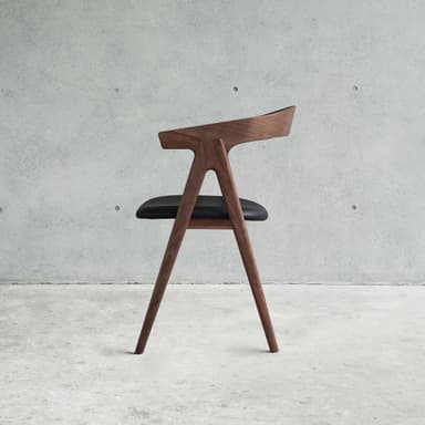 A modern armchair with a curved wooden frame and a black upholstered seat. The chair has four angled legs, a curved backrest that extends into armrests, and a distinctively shaped seat. — 3D model