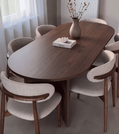 A contemporary dining table with an oval-shaped tabletop supported by a single, tapered pedestal base. The wood grain is clearly visible and runs across the surface. — 3D model