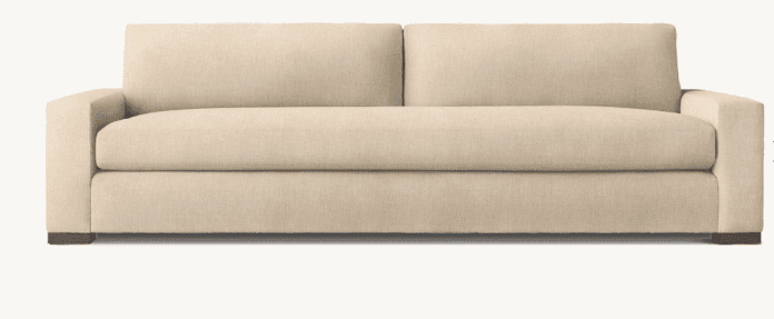 A contemporary two-seater sofa upholstered in a light beige, textured fabric. It features clean lines, track arms, and two plush seat cushions paired with two back cushions. The sofa sits on low, dark block feet. — 3D model