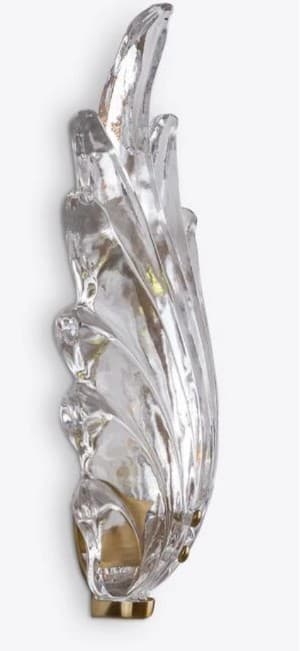A decorative wall sconce featuring a clear, sculpted glass element resembling organic forms, possibly inspired by nature or flames. The glass is multi-faceted, creating reflections and refractions of light. It is mounted on a metallic base with visible mounting points. — 3D model
