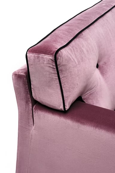 A close-up view of a sofa section, showcasing plush velvet upholstery in a dusty rose color. The sofa features a tufted back cushion with a black button accent and decorative black piping along the edges of the headrest and armrest. The material appears soft and textured, indicative of velvet. — 3D model