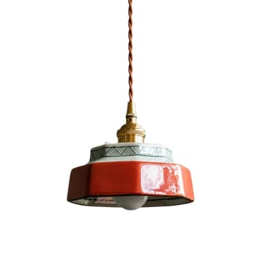 A decorative pendant light featuring an octagonal ceramic shade with a two-tone design. The lower section of the shade is a vibrant glossy red glaze, while the upper section is white with a repeating green geometric pattern. The ceramic shade is suspended by a brass fitting and a twisted brown fabric electrical cord. A small, spherical bulb is visible at the bottom of the shade. — 3D model