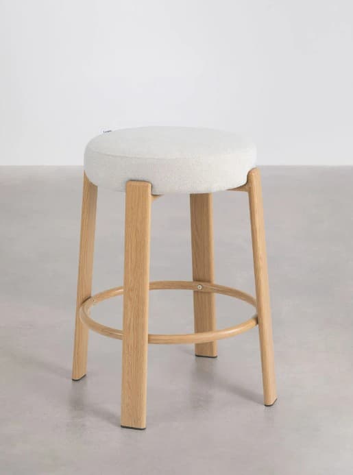 A modern stool featuring a round, light-colored upholstered seat and four splayed wooden legs, connected by a circular wooden footrest. — 3D model