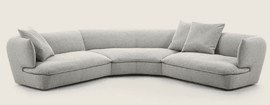 A curved sectional sofa upholstered in a light grey textured fabric. It features a low profile with rounded armrests and deep seating. Two matching throw pillows are placed on the sofa. — 3D model