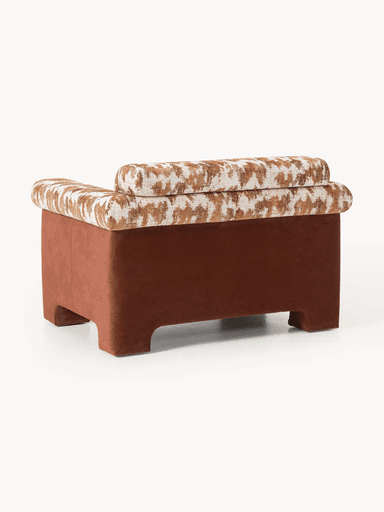A single-seater armchair with a low profile and wide armrests. The seat and back cushions feature a textured geometric pattern in brown and off-white. The base and outer frame are upholstered in a solid, muted reddish-brown fabric. The armchair has a contemporary design with integrated block feet. — 3D model