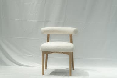 A contemporary side chair with a rounded backrest and seat upholstered in a textured, boucle fabric. The chair features a light-colored wooden frame with four tapered legs. The design is minimalist and modern. — 3D model