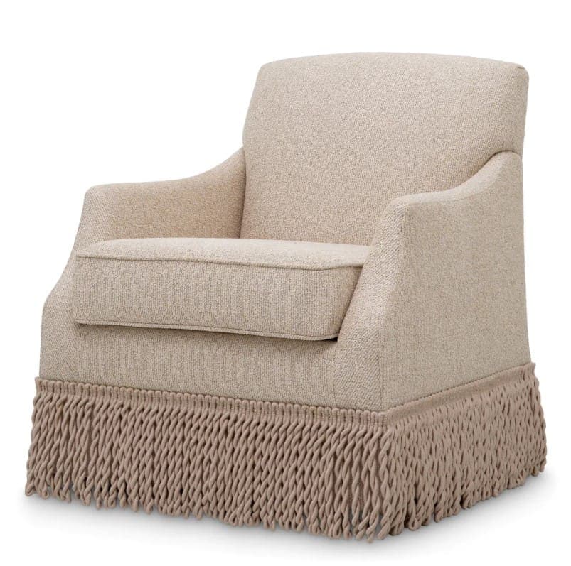 A light beige armchair with a textured fabric upholstery. The chair features a boxy seat cushion and rounded arms. The base of the chair is adorned with a thick, braided fringe that extends to the floor. — 3D model