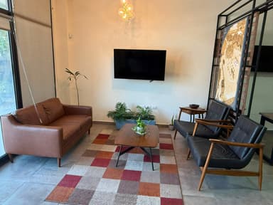 A contemporary or mid-century modern two-seater sofa, upholstered in warm brown leather, featuring clean lines, track arms, and four slender, tapered wooden legs. — 3D model