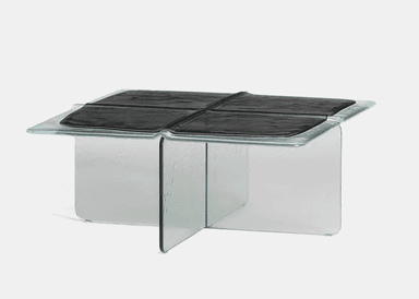 A contemporary coffee table constructed primarily from thick, clear glass. The design features a square tabletop with gently rounded edges and a central recessed area containing four distinct, textured black panels, possibly a form of faux leather or polymer. The base is formed by two intersecting glass panels, creating a stable cross-shaped support structure. The overall aesthetic is minimalist and sculptural, highlighting the material properties of glass and the contrast with the dark, textured surface. — 3D model