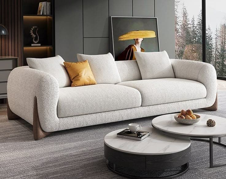 A contemporary two-seater sofa featuring a light, textured fabric upholstery and prominent dark wood accents. The sofa includes two large seat cushions and four back cushions, with one additional small accent pillow in a mustard yellow hue. The armrests are softly curved and upholstered, with the dark wood frame extending from the base upwards to form part of the armrest structure, creating a sleek and modern profile. — 3D model