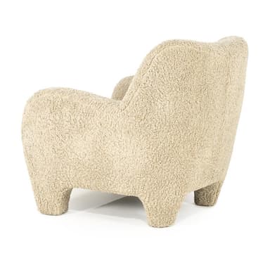 A cream-colored armchair with a rounded silhouette, upholstered in a textured fabric resembling boucle or sherpa. It features broad, enveloping arms, a high back, and four short, chunky legs. A small, square throw pillow with matching upholstery is placed on the seat against the back. — 3D model