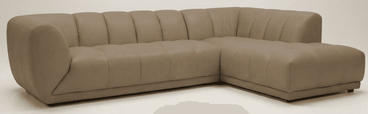 A modern sectional sofa upholstered in taupe leather, featuring distinct channel tufting on the backrests and seat cushions, and an integrated right-hand facing chaise lounge. — 3D model