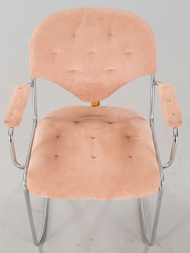 A cantilever armchair with a tubular chrome-plated steel frame. The seat, backrest, and armrests are upholstered in a tufted, salmon-pink, velvety fabric. The backrest has a distinct curved shape and is attached to the frame with leather straps. The armrests are also padded and follow the curvature of the frame. — 3D model