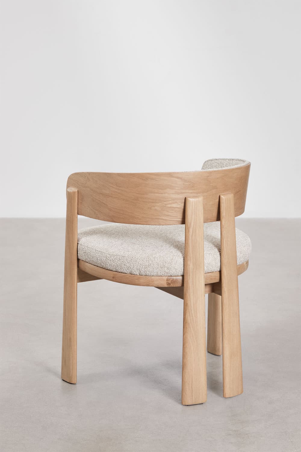 A modern dining chair featuring a solid light oak wood frame and light-colored textured fabric upholstery. The chair has a gently curved backrest that seamlessly transitions into integrated armrests, forming a barrel-like shape. The legs are robust and subtly tapered, contributing to its minimalist and contemporary aesthetic. The seat and inner backrest are cushioned. — 3D model