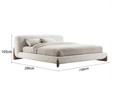 A modern platform bed featuring a generously padded, rounded headboard and frame, entirely upholstered in a light, off-white bouclé fabric. The bed maintains a low-profile design and is supported by four subtly tapered dark wooden feet, two visible at the head and two at the foot, seamlessly integrating into the minimalist aesthetic. It is presented with a neutral-toned mattress, two pillows, and a duvet. — 3D model