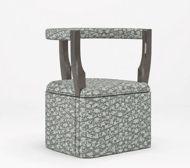 A compact upholstered club chair with a distinctive open backrest and integrated armrests. The chair features a cubic base entirely covered in a patterned fabric, displaying an intricate, possibly organic or geometric, design in light gray against a muted blue-green background. The visible frame elements of the back and arms are made of dark brown wood with a smooth, polished finish. — 3D model