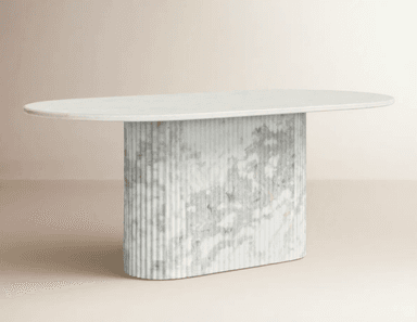 A contemporary dining table featuring an oval white marble tabletop supported by a substantial fluted pedestal base made of grey and white veined marble. The base has a rounded, pill-like shape, complementing the oval top. — 3D model