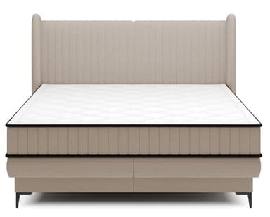 A contemporary upholstered bed featuring a distinctive wingback headboard and an integrated box spring base. The entire structure, including the headboard and base, is covered in a soft beige fabric with vertical channel tufting on the headboard and upper box spring. The bed is supported by subtle, tapered black metal feet. A white mattress with black piping is positioned on top of the box spring. — 3D model