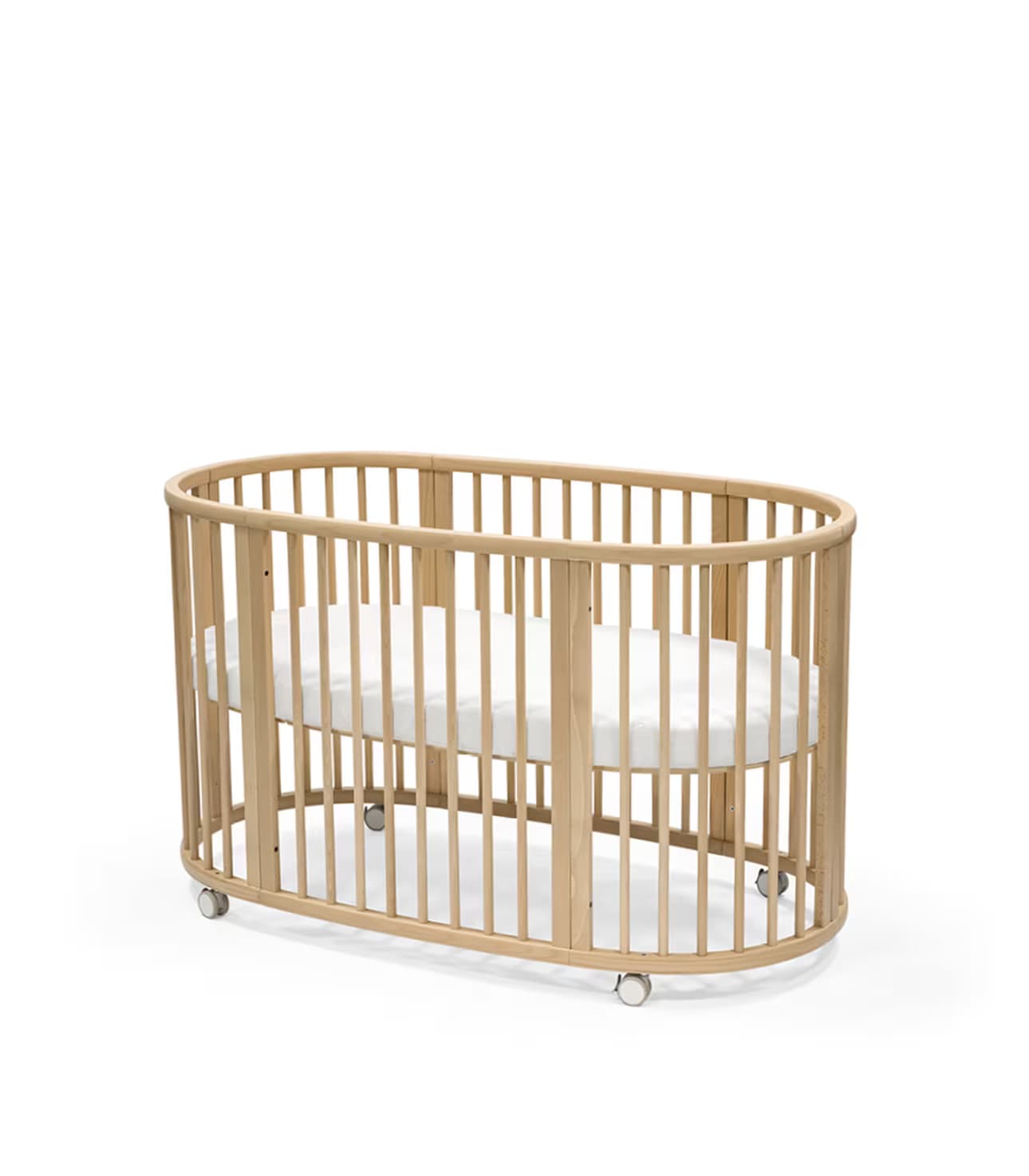 An oval-shaped baby crib crafted from light-toned wood, featuring vertical slatted sides for visibility and breathability. The crib is supported by small casters at its base, indicating mobility. A white mattress is visible within the crib, conforming to its oval shape. The design is modern and minimalist, emphasizing natural materials and a gentle aesthetic. — 3D model