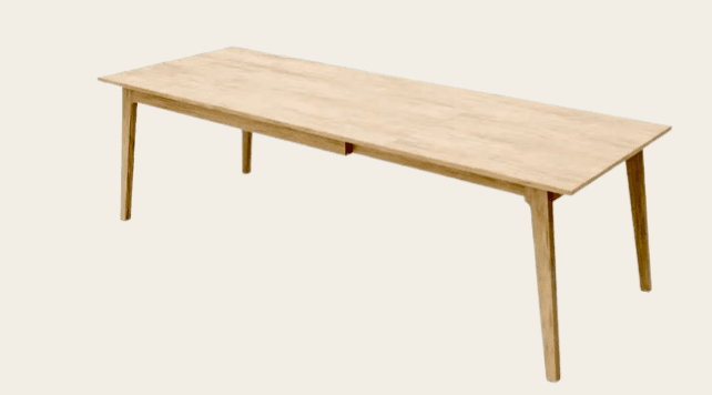 A rectangular dining table with a light wood finish. It has a plain tabletop with no visible extensions or complex joinery. The table is supported by four tapered legs that splay outwards. There appears to be a subtle drawer pull or inset detail on one of the longer sides, centrally located. — 3D model